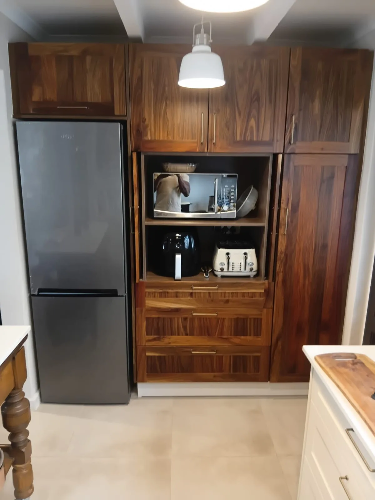 Appliance Garage, Doors Open — The same timber wall with its appliance garage open: microwave, air fryer and toaster on their own shelves behind a pair of pocket doors, so the worktop stays clear and the kitchen looks finished when the doors are shut.